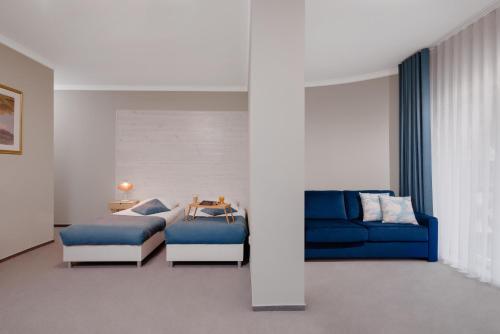 a living room with a blue couch and a bed at Plaża Resort in Bogaczewo