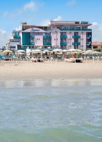 a beach with chairs and umbrellas in front of a hotel at Hotel Lungomare in Cesenatico