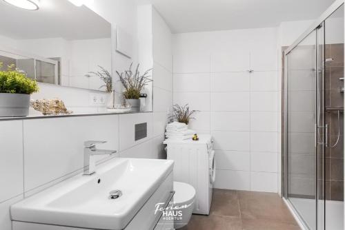 ein weißes Bad mit einem Waschbecken und einem WC in der Unterkunft Küstenwind in Olpenitz