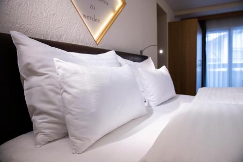 a white bed with white pillows on top of it at Hotel Tirol Fiss 4Sterne Superior in Fiss