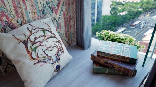 a stack of books sitting on a window sill with a pillow and flowers at K Hotel - Yizhong in Taichung