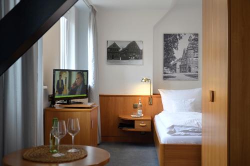 a hotel room with a bed and a tv and a table at Haus Luisenhof in Mölln