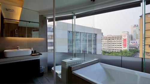 a bathroom with a tub and a sink and a window at K Hotel - Yizhong in Taichung