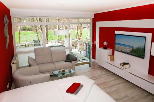 - un salon rouge avec un canapé et une télévision dans l'établissement Appartementhaus Sanssouci, à Kühlungsborn