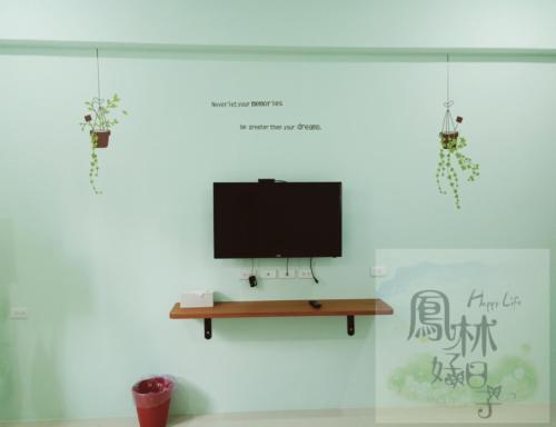 einen TV an einer weißen Wand mit einem Tisch in der Unterkunft 鳳林好日子 in Fenglin