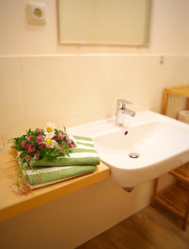 ein Badezimmer mit Waschbecken und einem Blumenarrangement auf einem Handtuch in der Unterkunft Vitaleum in Krölpa