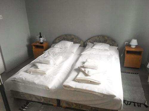 a bed with white sheets and pillows on it at Tompos Vendégház és pince in Villány