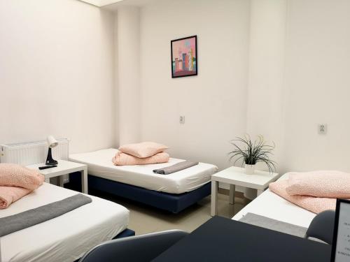 a room with three beds with pink pillows on them at Hostel Kamienica Rynek 7 in Katowice