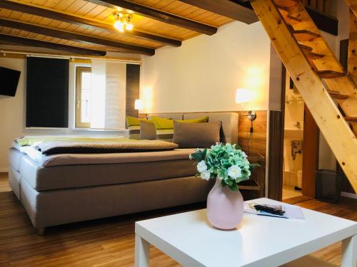 a bedroom with a bed and a table with a vase of flowers at Pension "Tor zum Rennsteig" in Hörschel