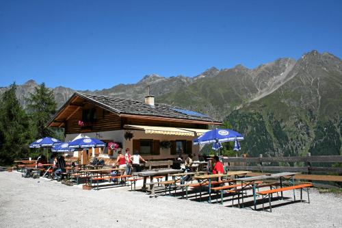 a restaurant with wooden tables and blue umbrellas at Hotel Wiese in Sankt Leonhard im Pitztal