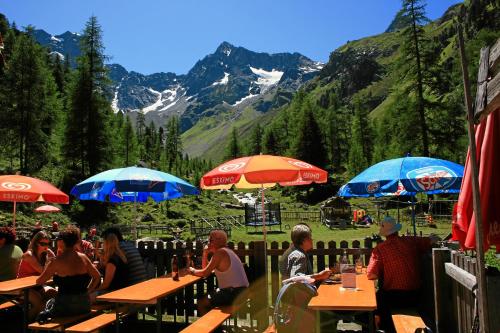 a group of people sitting at tables with umbrellas at Hotel Wiese in Sankt Leonhard im Pitztal