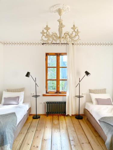 two beds in a white room with a chandelier at Villa Gaida in Saulkrasti