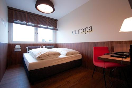 a bedroom with a bed with a desk and a sign on the wall at Hotel Europa Life in Frankfurt/Main