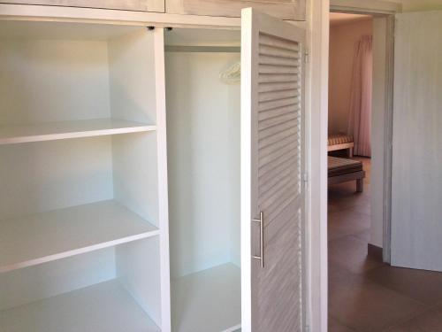 um armário com prateleiras brancas e uma porta em APARTAMENTS BLAU MAR em Es Migjorn