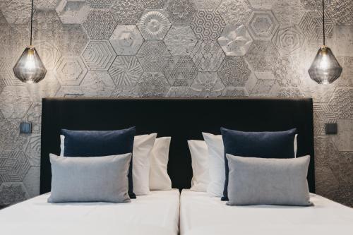 um quarto com uma cama com almofadas e uma parede em Obidos Aquae Ductus Suites em Óbidos