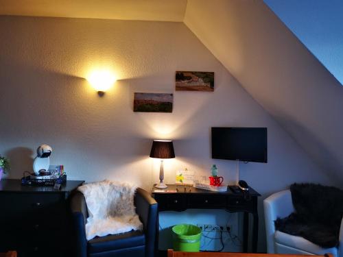um quarto com 2 cadeiras e uma secretária com uma televisão em Casa Mia Pension am Mailandsberg - Klima em Lutherstadt Wittenberg