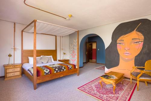1 dormitorio con 1 cama y una pintura de una mujer en Selina Quito, en Quito