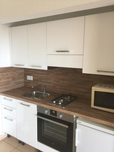 une cuisine avec des armoires blanches, un évier et une cuisinière dans l'établissement Appart'Hôtel A Punta, à Galéria