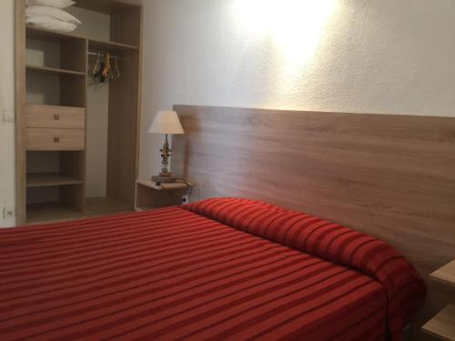 a bedroom with a red bed with a wooden headboard at Appart'Hôtel A Punta in Galeria