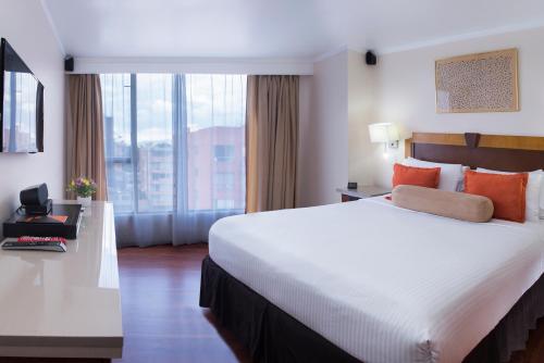 a hotel room with a large bed and a large window at Lancaster House in Bogotá