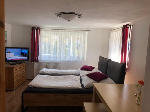 a room with a bed and a table and a television at Guest Appartements mit 2 getrennten Schlafzimmern für 4 Personen 24h check in in Aalen