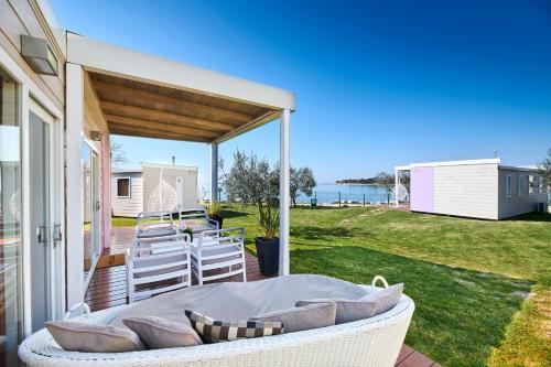 a patio with a couch and chairs on a deck at Mobile Homes Sunset Beach in Umag