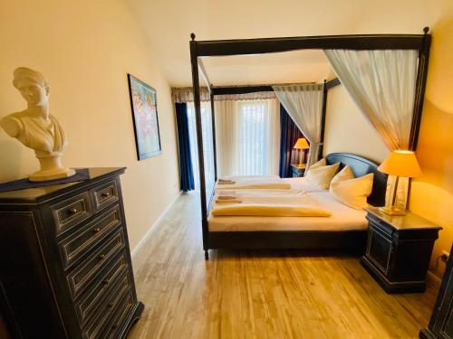 ein Schlafzimmer mit einem Himmelbett und einer Kommode mit einer Lampe in der Unterkunft Residenz Bleichröder - Ferienwohnung Aurelia in Heringsdorf