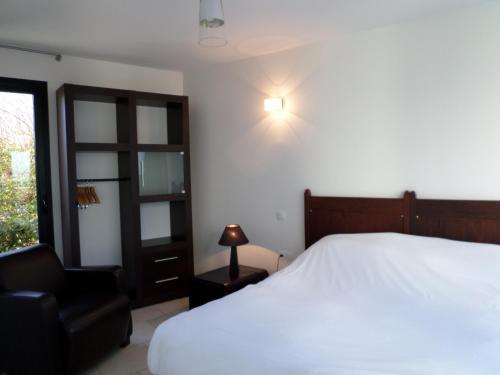 - une chambre avec un lit blanc et une chaise noire dans l'établissement Gîtes " Arromanches" ou "Bord de Mer PMR" 2 chambres en FRONT DE MER à Asnelles , 3km d'Arromanches, 10km de Bayeux, à Asnelles