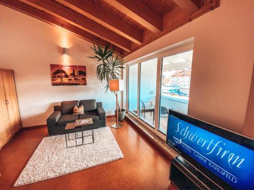 a living room with a couch and a tv at Hotel Schwertfirm in Karlsfeld