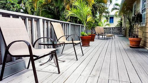 a wooden deck with chairs and plants on it at Authors Key West Guesthouse in Key West