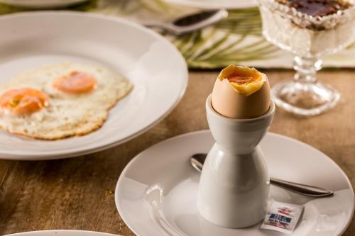 Solar Da Serra Tiradentes في تيرادينتيس: بيضة على طبق أبيض بجانب طبق من الطعام