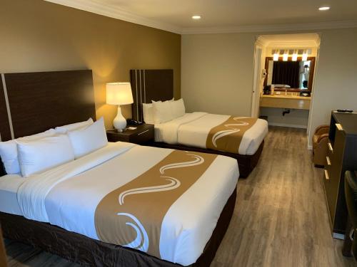 a hotel room with two beds and a bathroom at Quality Inn Long Beach - Signal Hill in Long Beach