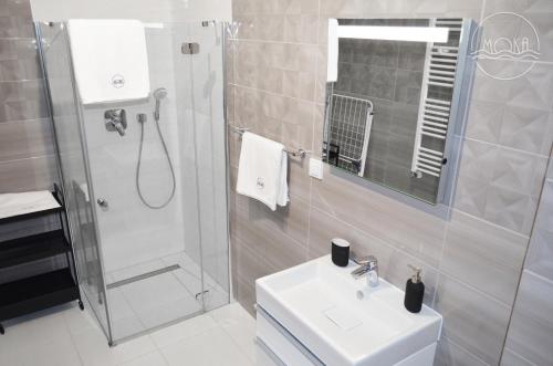 a bathroom with a sink and a shower and a toilet at MoKa Apartamenty Sianożęty in Sianozety