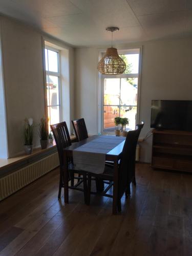 a dining room with a table and chairs and a television at Sfeervol 't Rustpunt in Bierum