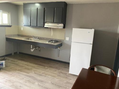 a kitchen with a white refrigerator and a sink at Valley Motel in Atwater