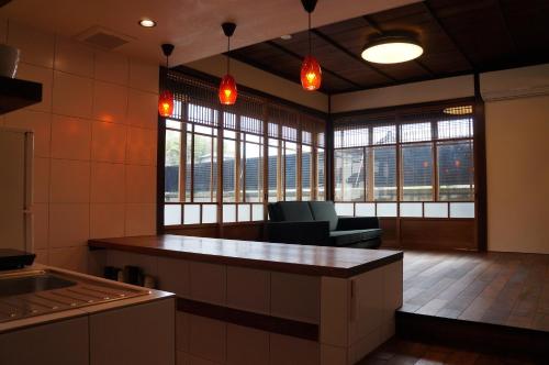 a kitchen with a counter and some chairs and windows at Moon's Cafe in Onomichi