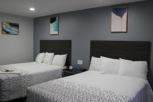 two beds in a hotel room with white sheets at SureStay Hotel by Best Western Chowchilla Yosemite in Chowchilla