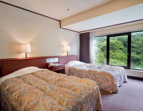 una camera d'albergo con due letti e una grande finestra di Okudogo Ichiyunomori a Matsuyama