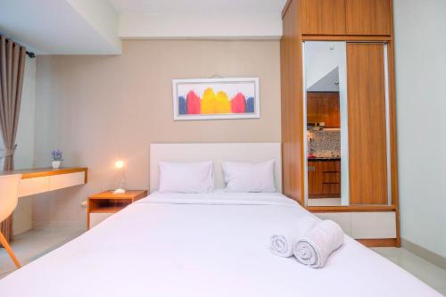a bedroom with a large white bed and a window at Homey and Relaxing Studio @ Grand Dhika City Apartment By Travelio in Padurenan
