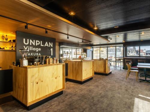 a restaurant with wooden counters and tables in a room at UNPLAN Village Hakuba in Otari