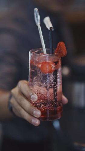 a hand holding a drink with a strawberry on it at Ayani Hotel Banda Aceh in Banda Aceh