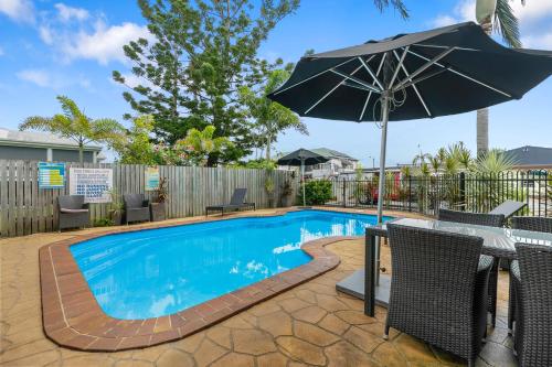 a swimming pool with a table and an umbrella at Best Western Kimba Lodge in Maryborough