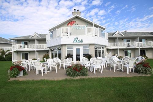 a large white building with white tables and chairs at Motel Grand-Pré Inc in Bonaventure