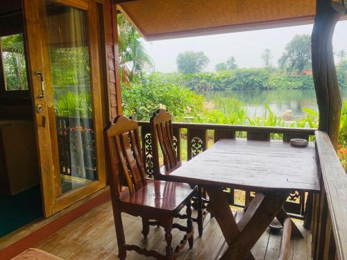 a table and chairs on a porch with a view of a river at Buasawan Resort & Restaurant in Kanchanaburi City