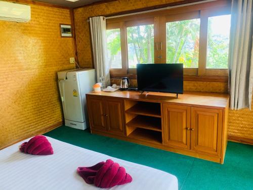a room with two beds and a desk with a television at Buasawan Resort & Restaurant in Kanchanaburi City