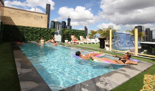 a group of people laying in a swimming pool at City Backpackers HQ in Brisbane