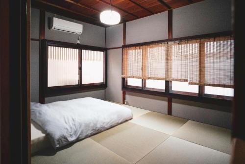 a room with a bed and two windows in it at Modern Machiya MIBU in Kyoto