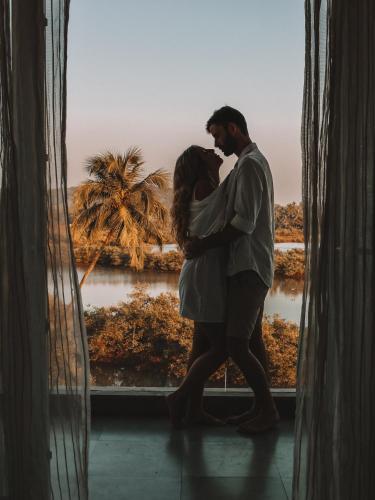 a man and a woman kissing in front of a window at The Park Baga River Goa in Baga