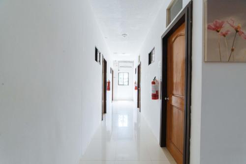 a hallway with white walls and a wooden door at RedDoorz Plus near Dadiangas Heights in General Santos