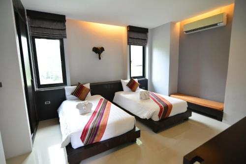 two beds in a room with two windows at Chaweng Noi Pool Villa in Chaweng Noi Beach
